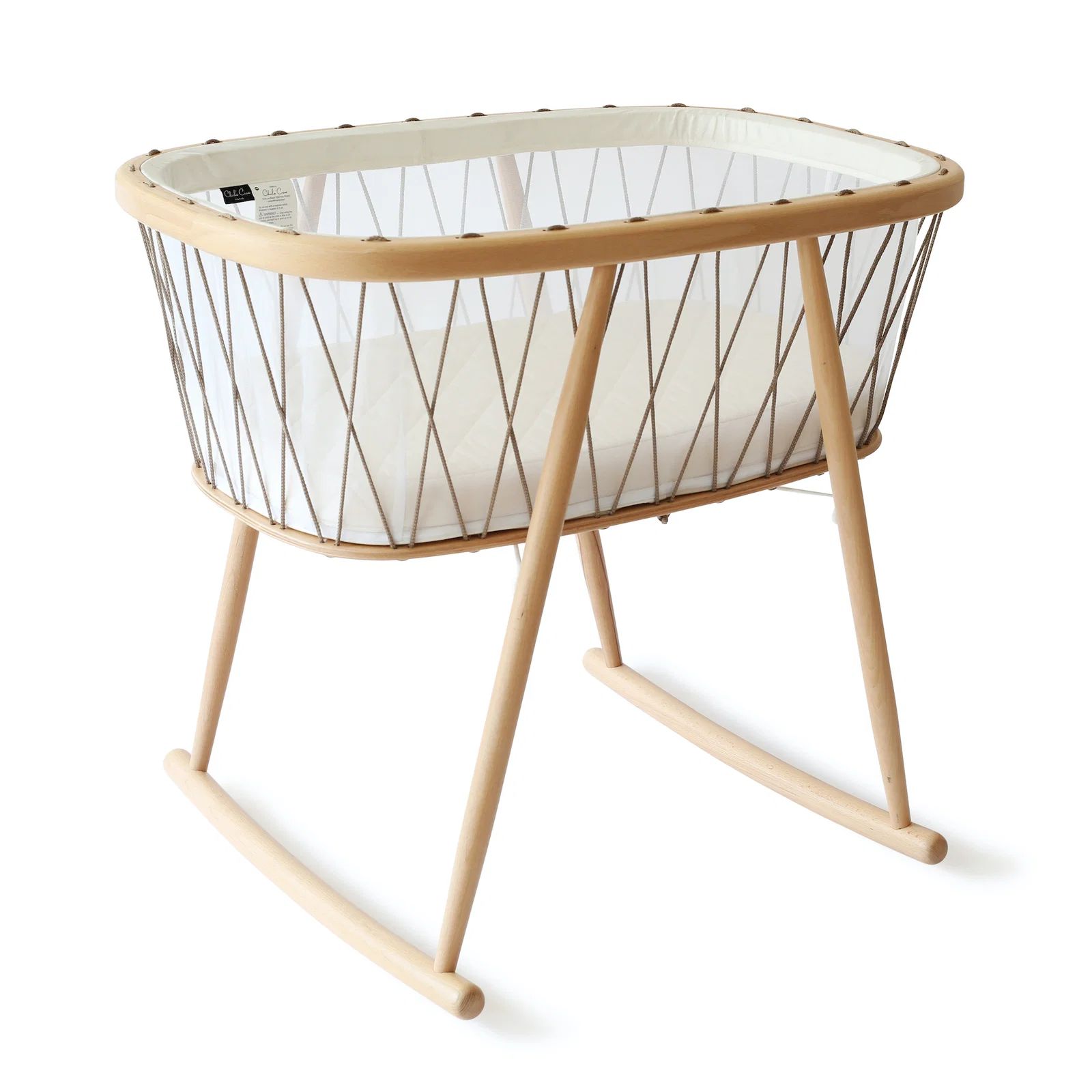 Kumi Bassinet in natural wood with woven rope sides, a white quilted mattress, and a minimalist rocking stand