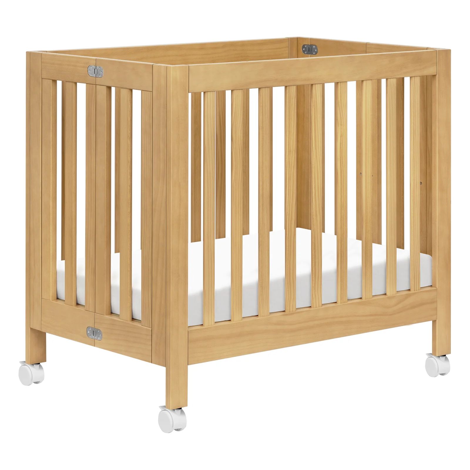 Natural wood Babyletto Origami mini crib with vertical slats, lockable caster wheels, and a white mattress